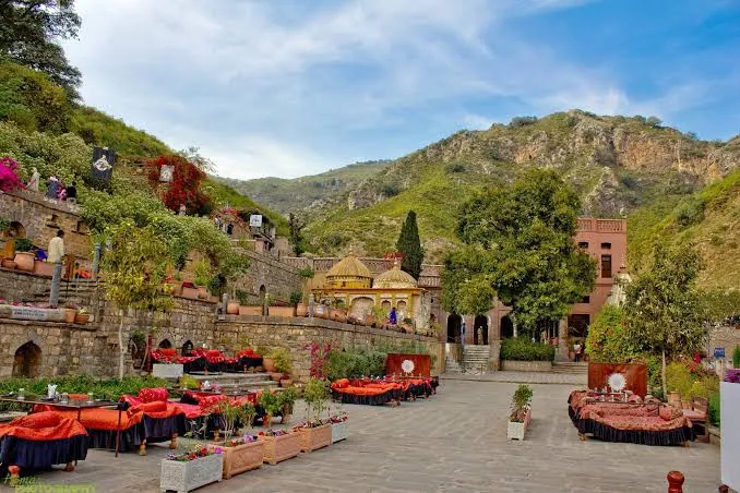 Restored Saidpur Village in Islamabad with terraces, red cushions and the Margalla Hills behind